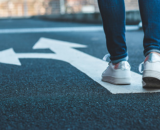 Feet moving towards arrows on a road