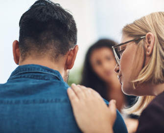 Male being comforted by female with hand on shoulder