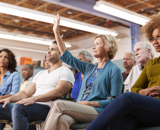 People sat at a public meeting with hands raised