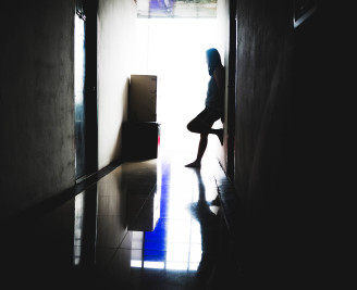 lone female standing in a dark corridor