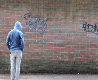 teenage boy wearing hoodie in front of wall