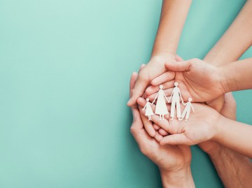 Paper cut out people held supportively by hands