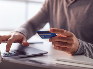 anonymous man keying card details into a laptop