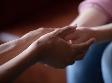 close up of female hands holding other hands in comforting way