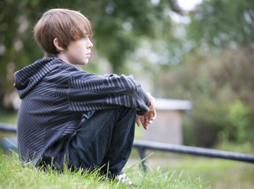 Young boy sitting in parkland