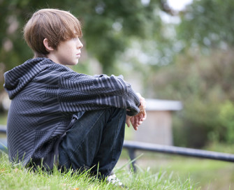 Young boy sitting in parkland