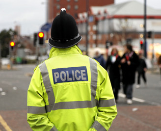 Back view of police officer outside wearing high visibility jacket 