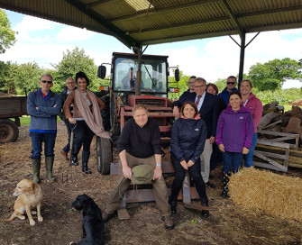 Former PCC Lorne Green standing with farmer and young people in hay barn