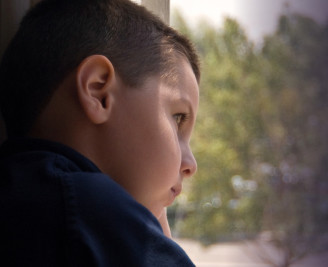 Close up of young boy looking out of window