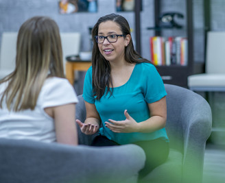 Two young women sat talking face to face 