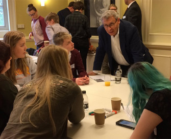 Former PCC Lorne Green leaning on table talking to group of young people