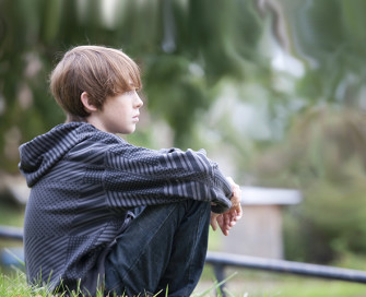 Young boy sat looking into distance